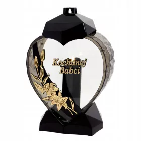    Eine große schwarz-goldene Kerze in Form eines Herzens mit einer Lilienblüte für Oma