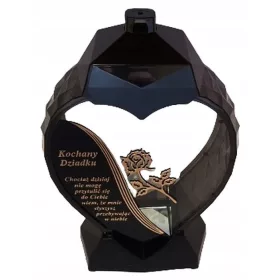    Eine große schwarz-goldene Kerze in Form eines Herzens mit einer Lilienblüte für Opa